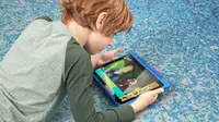 Child on floor watching fire tablet with PBS Kids Wild Kratts episode on the screen.