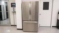 Front view of the silver LG LRFLC2706S Refrigerator against a wall in a white-walled product testing laboratory.