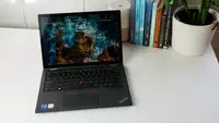 Lenovo ThinkPad L13 Yoga Gen 4 sitting on white surface next to potted plant and row of books.
