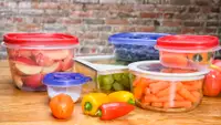 Several food strage containers filled with fresh produce on a wooden surface