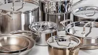 Several stainless steel pots and pans crowded together on a white surface