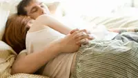 A couple asleep in bed cuddling