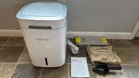 The Reencle Home Composter, which comes with an instruction manual, package of microbes, filters, and scoop.