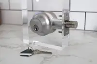 The Level Lock Plus Connect smart deadbolt set up on a test stand with a key and fob on the counter