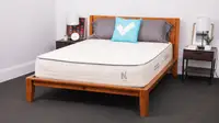 The Nolah Natural mattress inside of a wooden bed frame in bedroom.