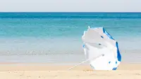 A blue and white umbrella blows in the wind