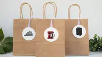 Three brown gift bags on a table with gift tags on them
