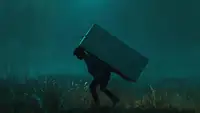 A person sneaking through the night with a refrigerator on their back