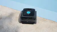 Aiper robotic pool cleaner sitting on the edge of a pool