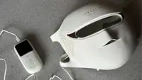 White Megelin LASER & LED mask and remote on grey surface.