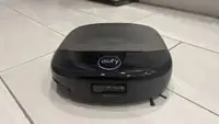A black robot vacuum on a beige tile floor