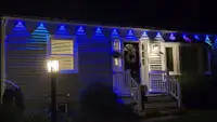 Govee Permanent Outdoor Lights 2 Pro illuminated in blue hung horizontally on a white house.