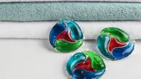 Three laundry pods placed next to folded towels