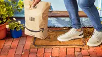 A person picks up an Amazon package from the front steps