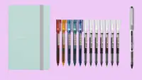 A mint-green notebook on the left is pictured with a variety of colorful Japanese pens.