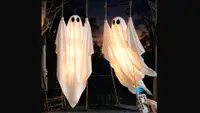 Two Dusfan swinging ghost decorations against a dark background.