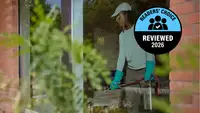A pest control specialist using chemicals behind glass in a brick building