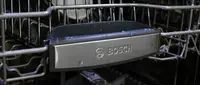 A close-up of the front of a Bosch dishwasher's top rack, which has the Bosch logo on it.