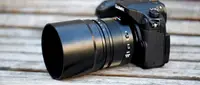 Angle on a black Lumix camera with a large zoom lens attachment on it.