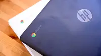 A close up of a black laptop placed on top of a white laptop