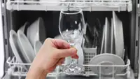 Someone examines a wine glass upon taking it out of a high end dishwasher.