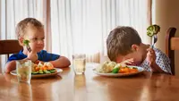 Two boys at a table refusing to eat