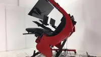 Red and black ergonomic workstation with large monitor tilted to a reclined position