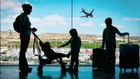 Mother at airport with three kids and luggage