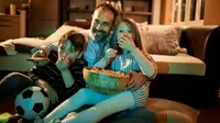Dad and two kids watching a movie at home