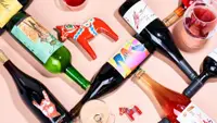 Assorted bottle of colorful wine arranged on a light pink surface.