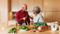 A couple laughs in their wood-paneled kitchen.