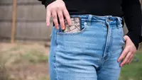 Girl wearing American Eagle jeans slides her cell phone into her pocket.