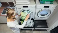 A person puts daily washing into the washing machine.