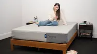 a woman sits on the Casper Original mattress looking at her phone in a bedroom.