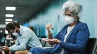 An older woman applies hand sanitizer in an airport waiting area