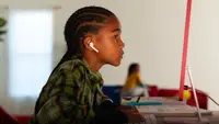 An image of a child sitting in front of the new iMac in red.