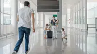 A family with three children in an airport pushing a suitcase