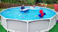 Three children swim and play in an above-ground Intex pool.