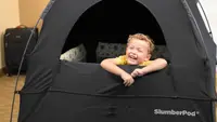 A child peeks out of a black SlumberPod.