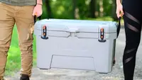 A man and a woman carrying an Ozark Trail cooler.