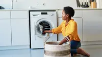 Woman doing laundry in her kitchen at home