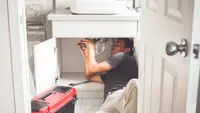 Person under sink fixing leak.
