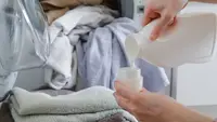 Hands pouring laundry detergent from bottle into cap