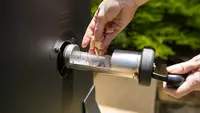 Girl putting wood chips into an electric smoker.