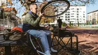 Person outdoors on sports court adjusting wheels for wheelchair.