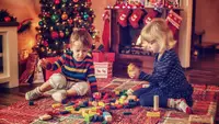 Boy and girl playing with blocks by a Christmas tree