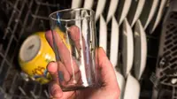 A hand holds a glass that's mostly clean, but has green flecks of redeposit marring its sheen.