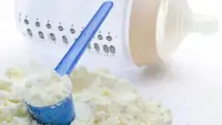 An image of powdered baby formula sitting on a counter near an empty baby bottle.