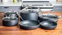 Charcoal colored pots and pans set on wooden countertop in kitchen.