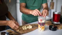 Two people chopping fruit and placing into a Magic Bullet blender for a smoothie